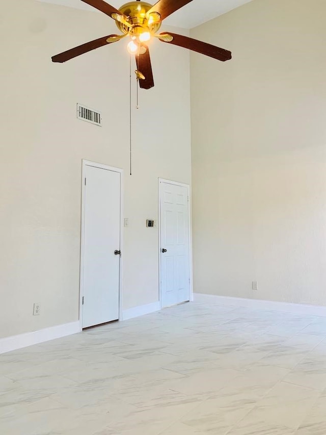 empty room with ceiling fan and a high ceiling