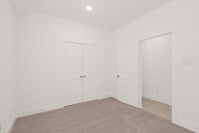 unfurnished bedroom with a closet and light colored carpet