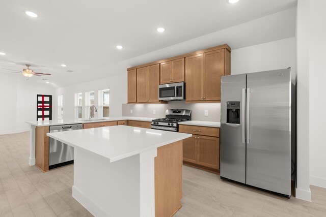 kitchen with kitchen peninsula, appliances with stainless steel finishes, light wood-type flooring, and a kitchen island