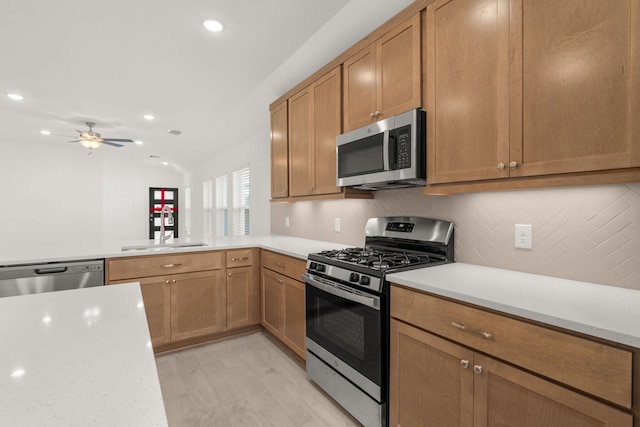 kitchen featuring ceiling fan, sink, stainless steel appliances, vaulted ceiling, and light wood-type flooring