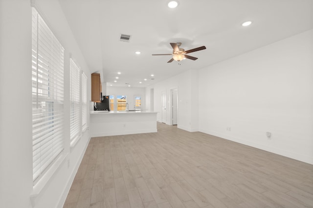 unfurnished living room featuring ceiling fan, light hardwood / wood-style flooring, plenty of natural light, and sink