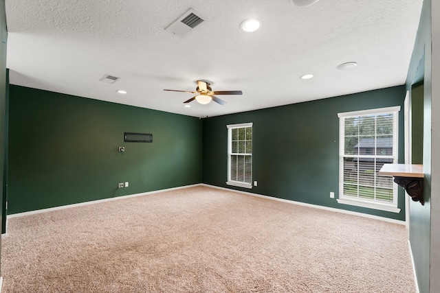 carpeted spare room featuring ceiling fan and a textured ceiling