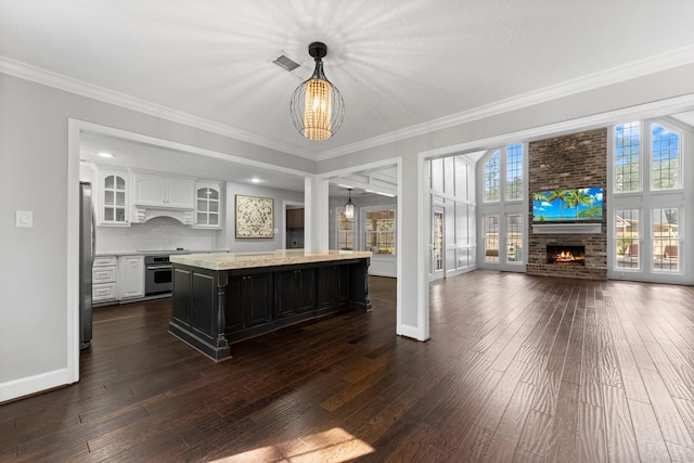 kitchen with dark hardwood / wood-style flooring, stainless steel appliances, white cabinetry, a kitchen island, and hanging light fixtures