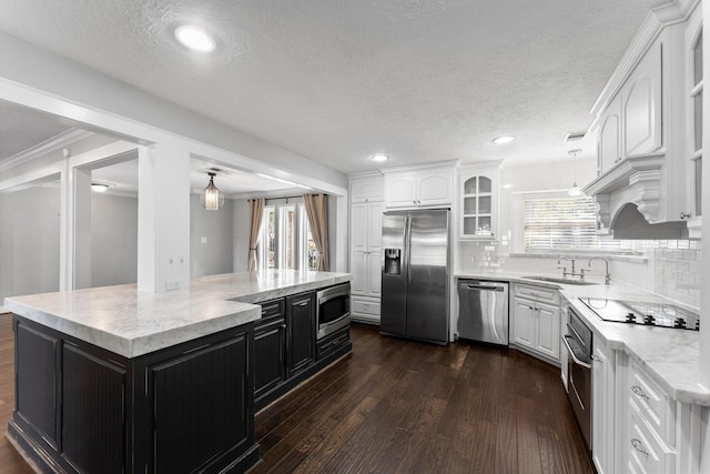 kitchen with stainless steel appliances, a kitchen island, dark hardwood / wood-style floors, and a healthy amount of sunlight