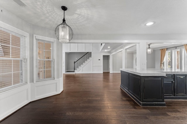 kitchen with light stone counters, a textured ceiling, dark wood-type flooring, decorative light fixtures, and an inviting chandelier