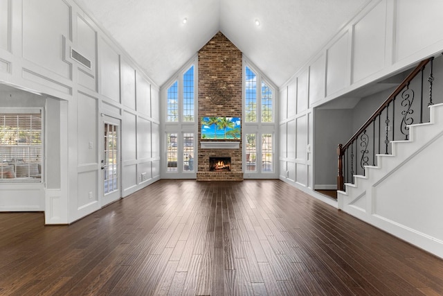 unfurnished living room featuring a fireplace, dark wood-type flooring, and high vaulted ceiling