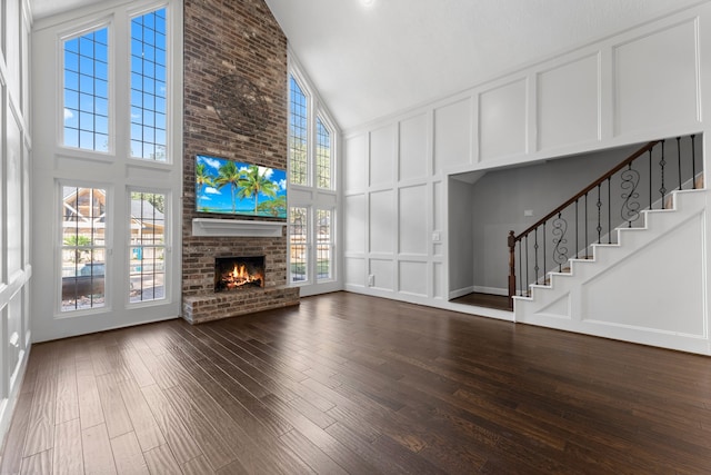 unfurnished living room featuring a fireplace, high vaulted ceiling, a healthy amount of sunlight, and dark hardwood / wood-style floors