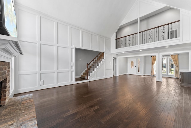 unfurnished living room with wood-type flooring, a towering ceiling, and a fireplace