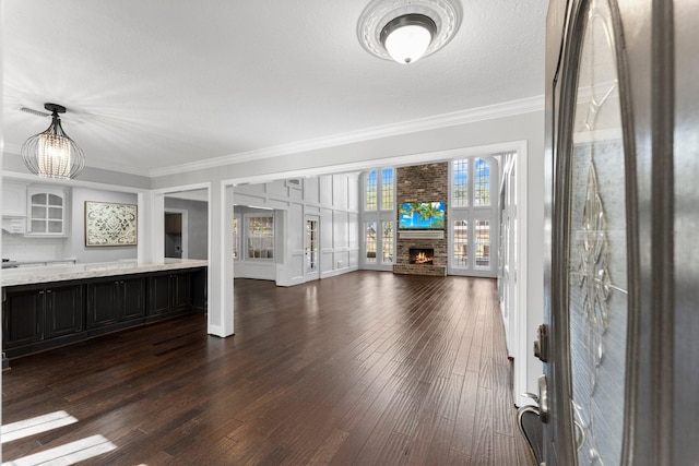 unfurnished living room with a textured ceiling, crown molding, a fireplace, and dark hardwood / wood-style floors