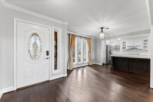 foyer entrance featuring ornamental molding, a textured ceiling, and dark wood-type flooring