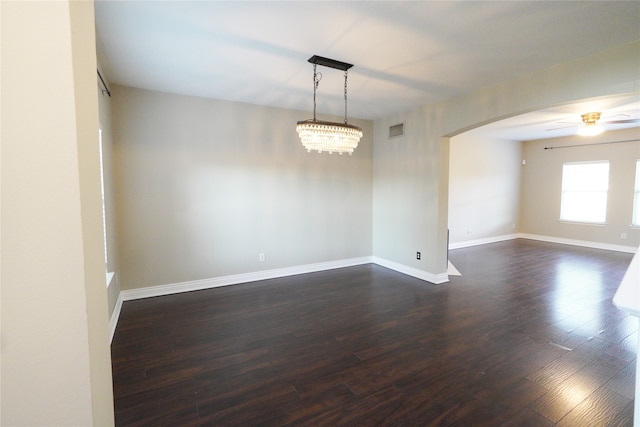 spare room featuring dark hardwood / wood-style floors and ceiling fan with notable chandelier