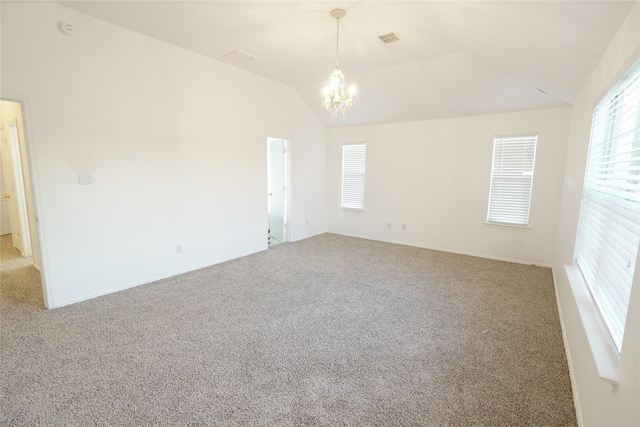 carpeted empty room featuring lofted ceiling and an inviting chandelier