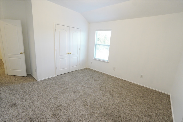 unfurnished bedroom featuring lofted ceiling, carpet flooring, and a closet