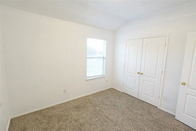 unfurnished bedroom featuring vaulted ceiling, carpet floors, and a closet