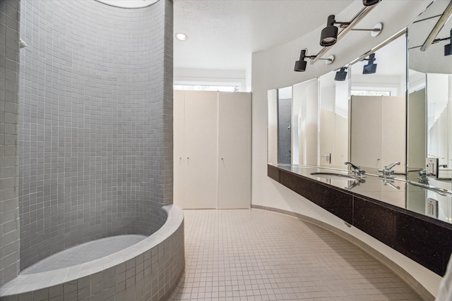 bathroom with tile patterned flooring, vanity, and tiled bath