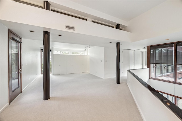 hallway with light carpet and a high ceiling