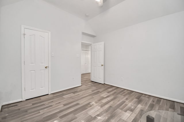 unfurnished bedroom with vaulted ceiling and light wood-type flooring