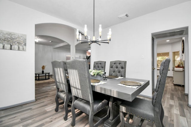 dining space with hardwood / wood-style floors and a notable chandelier