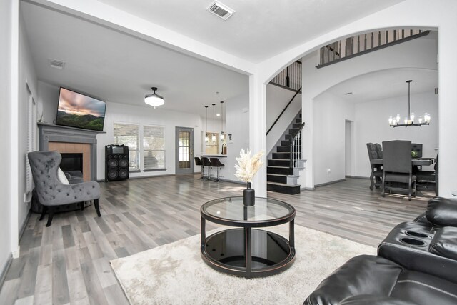 living room featuring hardwood / wood-style floors, a tiled fireplace, and a chandelier