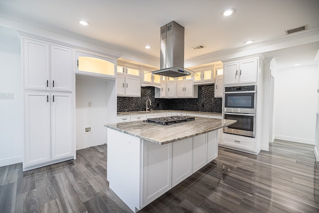 kitchen featuring island exhaust hood, a kitchen island, light stone countertops, white cabinetry, and appliances with stainless steel finishes