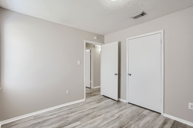 unfurnished bedroom featuring a textured ceiling and light hardwood / wood-style floors