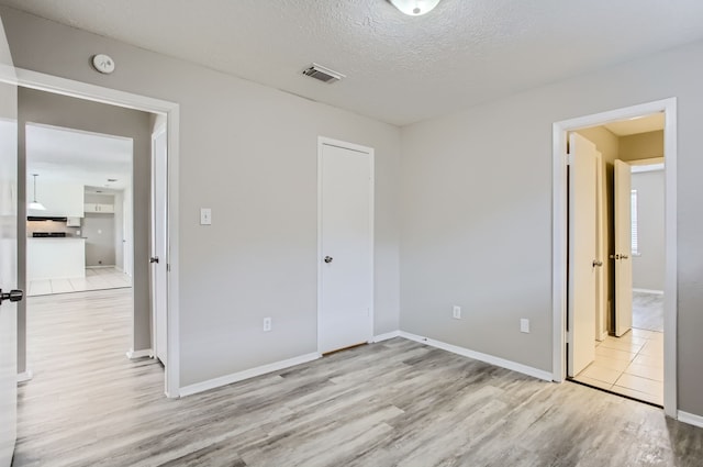 unfurnished bedroom featuring light hardwood / wood-style floors and a textured ceiling