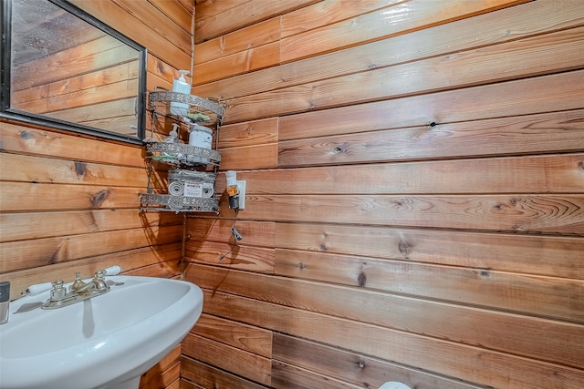 bathroom featuring sink and wood walls