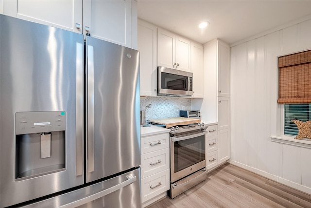 kitchen featuring decorative backsplash, white cabinets, stainless steel appliances, and light wood-type flooring