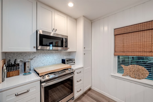 kitchen featuring light hardwood / wood-style floors, tasteful backsplash, appliances with stainless steel finishes, and white cabinets