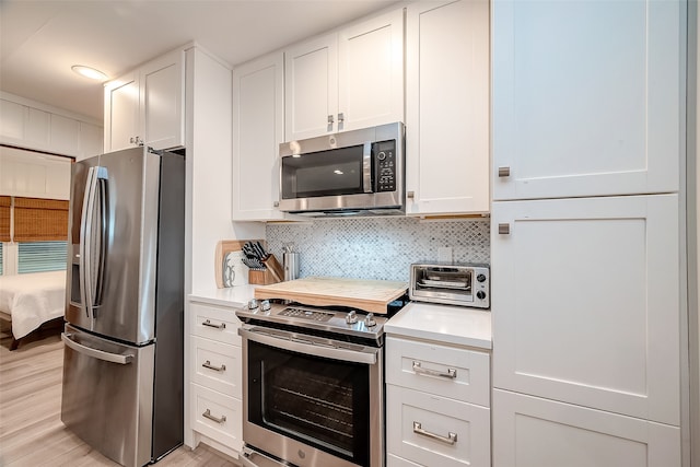 kitchen with decorative backsplash, light hardwood / wood-style flooring, white cabinets, and stainless steel appliances