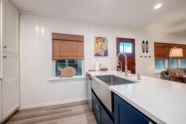 kitchen with white cabinetry, blue cabinetry, light hardwood / wood-style flooring, dishwasher, and sink