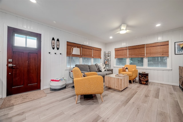 living room with ornamental molding, light hardwood / wood-style flooring, and ceiling fan