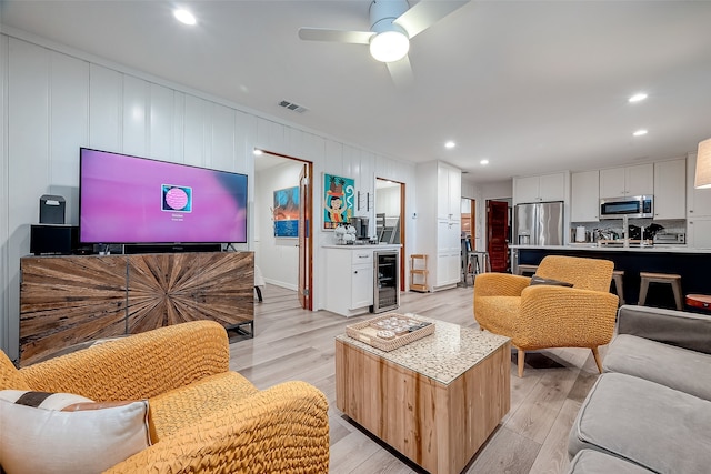 living room with wine cooler, light hardwood / wood-style floors, and ceiling fan