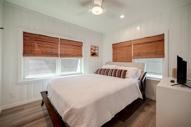 bedroom featuring multiple windows, hardwood / wood-style floors, and ceiling fan