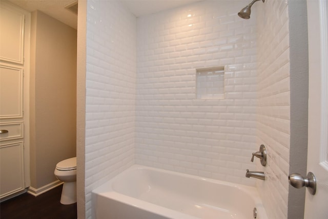 bathroom with wood-type flooring, tub / shower combination, and toilet