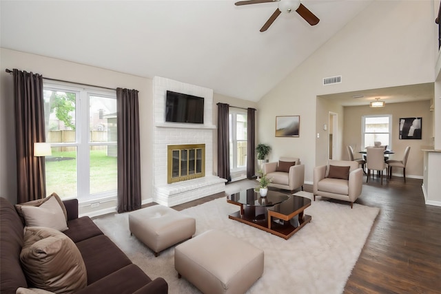 living room featuring ceiling fan, high vaulted ceiling, dark hardwood / wood-style floors, and a brick fireplace