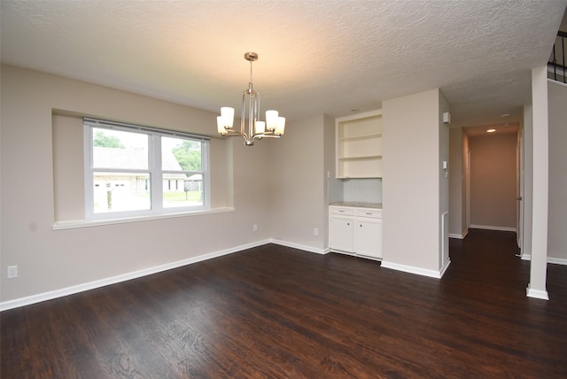 spare room featuring dark hardwood / wood-style floors, a textured ceiling, and a chandelier