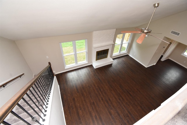 unfurnished living room featuring ceiling fan, a fireplace, dark wood-type flooring, and vaulted ceiling