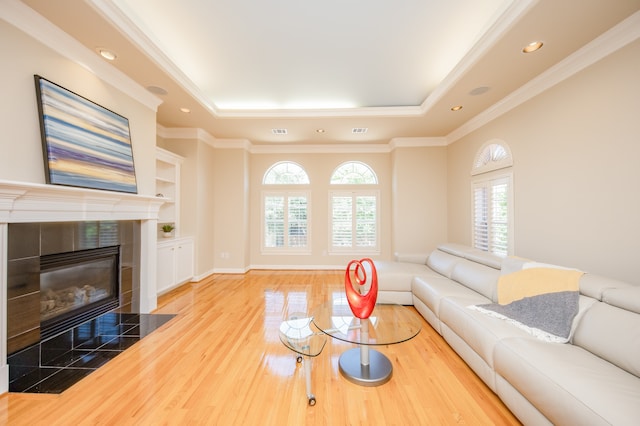 living room featuring ornamental molding, hardwood / wood-style floors, and a tiled fireplace