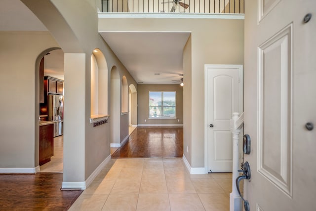 foyer with light hardwood / wood-style floors, a towering ceiling, and ceiling fan