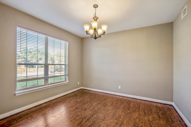 spare room featuring hardwood / wood-style flooring, a healthy amount of sunlight, and a chandelier