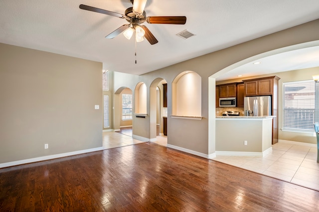 unfurnished living room featuring ceiling fan, a textured ceiling, and light hardwood / wood-style flooring