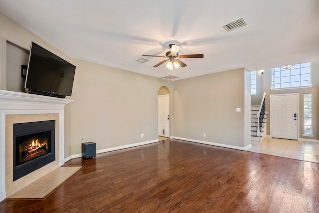 unfurnished living room featuring hardwood / wood-style floors, a tiled fireplace, and ceiling fan