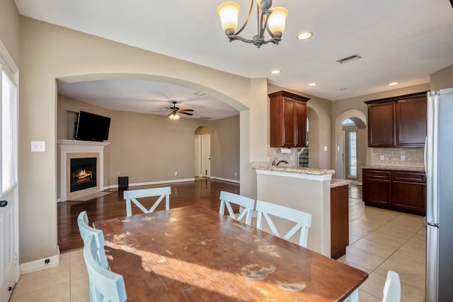 tiled dining area with ceiling fan with notable chandelier