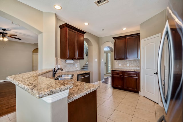 kitchen with appliances with stainless steel finishes, kitchen peninsula, sink, and light stone counters