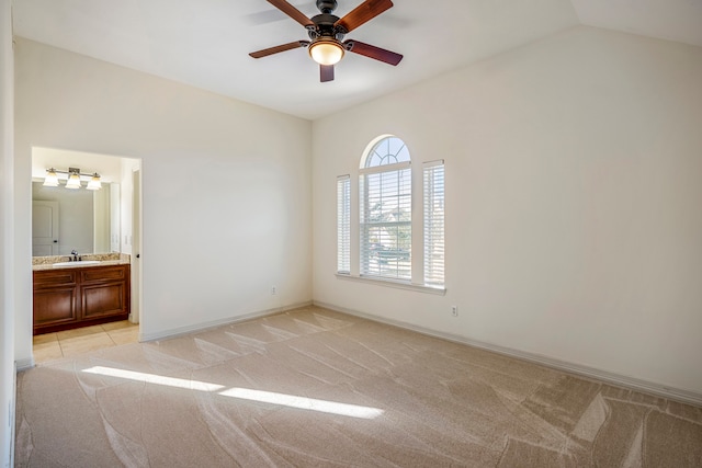 unfurnished bedroom featuring connected bathroom, sink, vaulted ceiling, light colored carpet, and ceiling fan