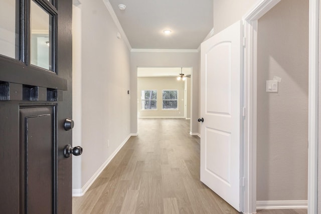 hallway with light wood-type flooring and crown molding