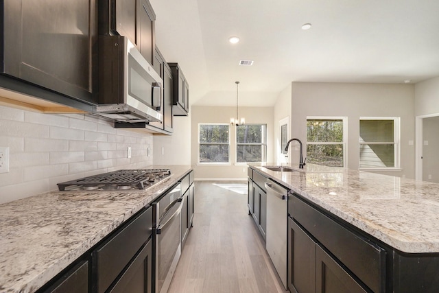 kitchen featuring sink, light hardwood / wood-style flooring, decorative light fixtures, stainless steel appliances, and a chandelier