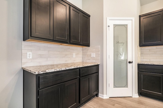 kitchen with backsplash, light stone countertops, and light hardwood / wood-style flooring