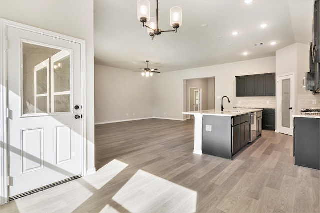 kitchen featuring sink, hanging light fixtures, light hardwood / wood-style flooring, a kitchen island with sink, and ceiling fan with notable chandelier